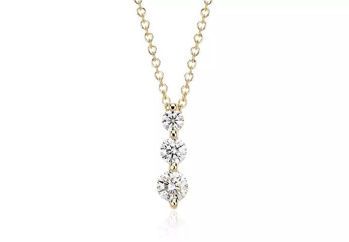 A three-stone diamond drop pendant symbolizes your past, present, and future, through three round brilliant-cut diamonds in graduated sizes set in shared, yellow gold prong settings hanging from a delicate yellow gold chain